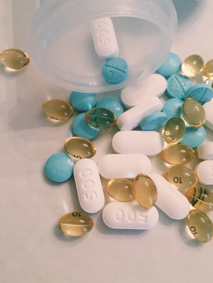 Tablets and capsules spilling from an open medicine bottle