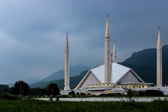 Faisal Mosque, Islamabad, lit at dusk below the Margalla Hills
